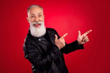 Portrait of attractive elderly cheerful grey-haired man showing copy space ad isolated over bright red color background.