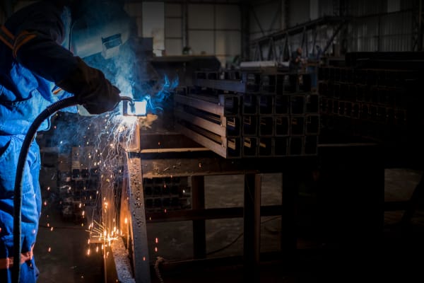 Schweißer bearbeitet Stahlprofile mit Funkenflug in der Metallindustrie