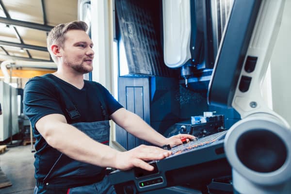 Mitarbeiter bedient die Steuerung einer Bearbeitungsmaschine im Rahmen der Maschinendatenerfassung