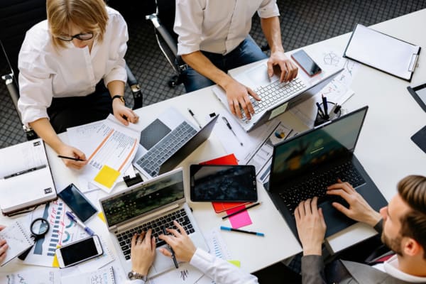 Planungsrunde am Tisch mit mehreren Laptops: ERP System Mittelstand in der Praxis