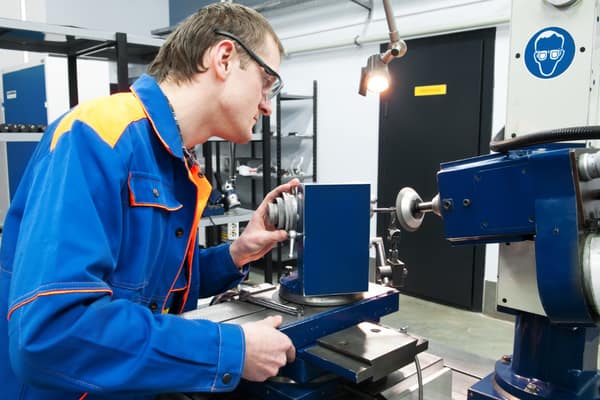 Facharbeiter richtet ein Bauteil an einer Dreh- und Schleifmaschine im Sondermaschinenbau aus