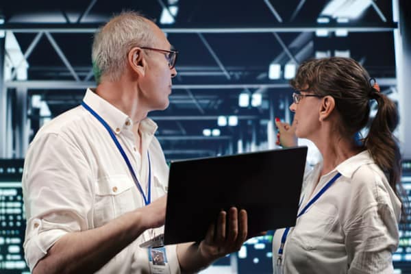 Zwei Kollegen besprechen Lieferantendaten anhand eines Laptops im Lager