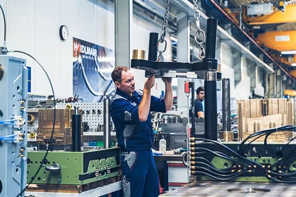 Mitarbeiter positioniert ein großes Formwerkzeug per Kettenzug - Fertigungssteuerung mit ERP Werkzeugbau