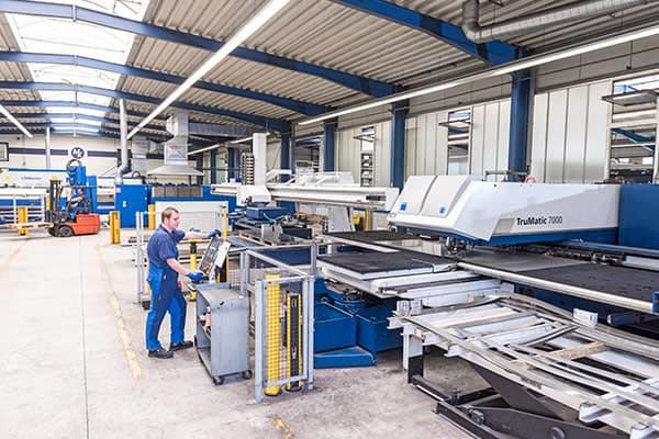 ERP Blechbearbeitung: Mitarbeiter bedient eine TruMatic Stanz-Laser-Maschine in der Produktionshalle