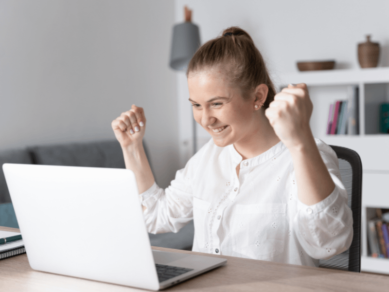 Meine Karriere24 2 Eine glückliche Bewerberin jubelt vor ihrem Laptop über eine erfolgreiche Job-Zusage auf Meine Karriere24.